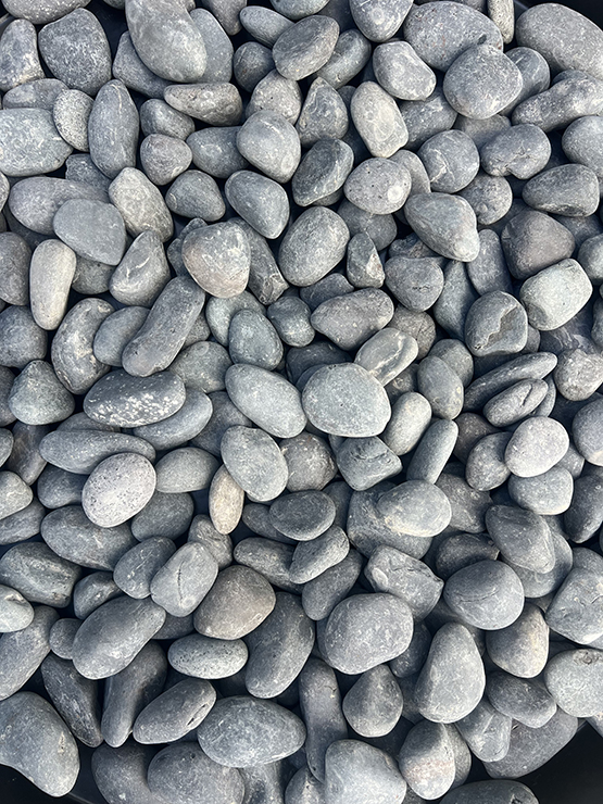 Blasted black pebbles installed in landscape bed